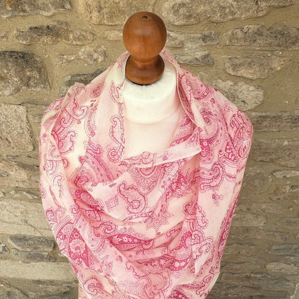 Pink paisley cashmere scarf on a mannequin against a stone wall background