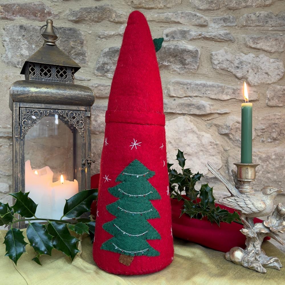 Bring festive charm to your home with this exquisite artisan handcrafted Father Christmas figure.

Meticulously created from premium felted wool, it showcases a luxuriously soft faux fur beard and intricate hand-stitched snowflake embellishments adorning the hat and body. The design features charming holly and berry appliqués on the hat, while the back displays an ornate Christmas tree decorated with sparkling beads. Shown on gold silk fabric with holly and festive candle and decorative items. 