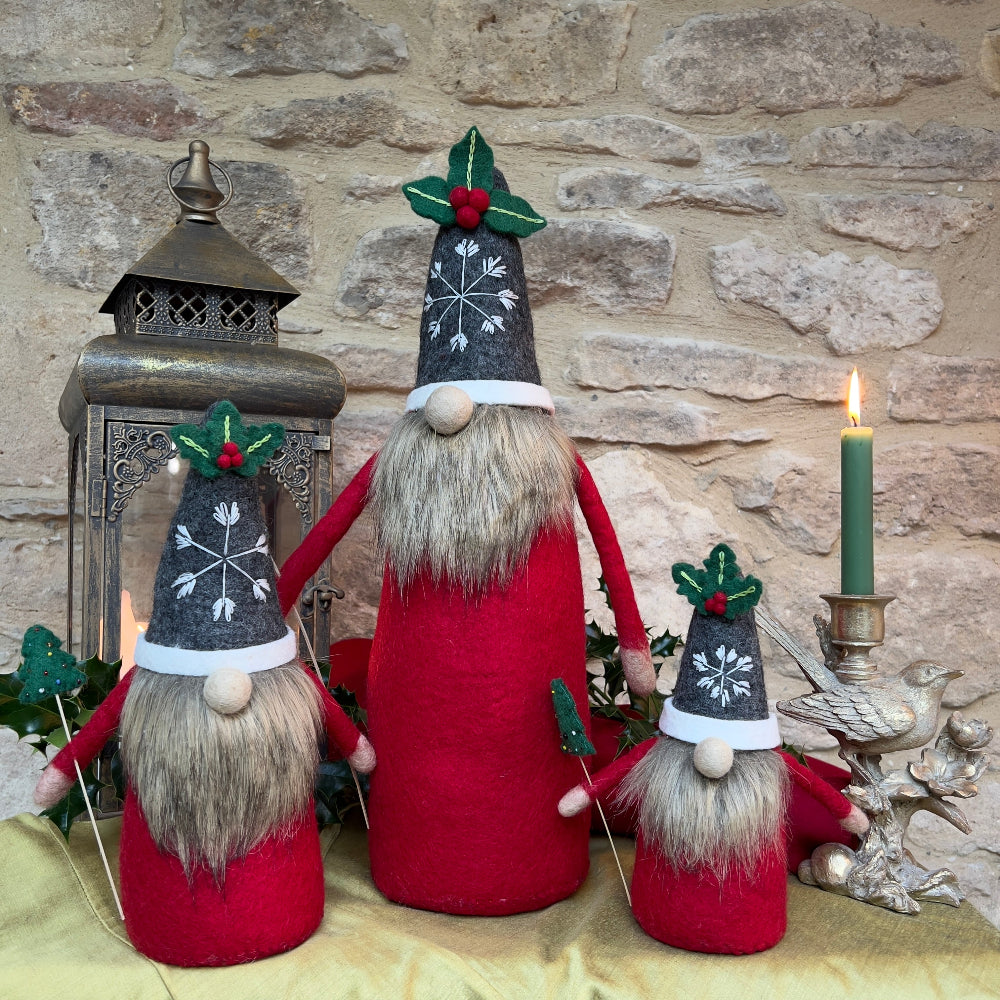 Elevate your festive décor with this exquisite handcrafted felted wool Father Christmas, a statement piece that brings authentic holiday charm to any space.

Handcrafted from pure felted wool, this impressive gnome commands attention with its luxurious faux fur beard and charming grey hat featuring a hand-stitched snowflake and festive holly appliqué with berries. The removable Christmas tree, adorned with intricate hand-sewn beads. Shown with holly, festive candles against a cotswold stone background. 