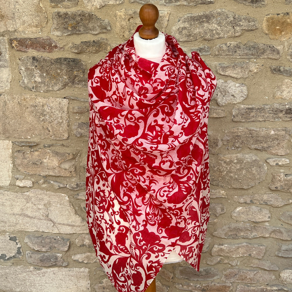 Red and white patterned gossamer cashmere pashmina scarf on a mannequin against a stone wall background