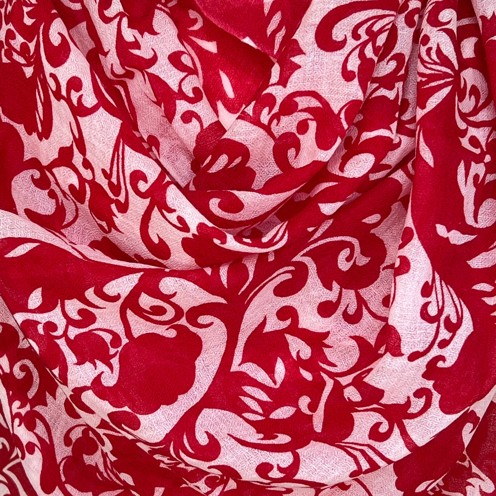 Red and white patterned gossamer cashmere pashmina scarf on a mannequin against a stone wall background