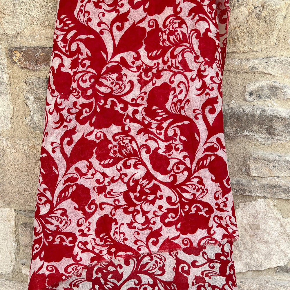 Red and white patterned gossamer cashmere pashmina scarf on a mannequin against a stone wall background