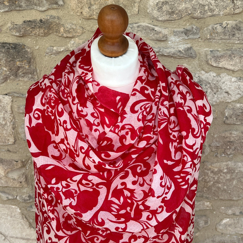 Red and white patterned gossamer cashmere pashmina scarf on a mannequin against a stone wall background