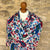 Red green and blue patterned gossamer cashmere pashmina on a mannequin against a stone wall background. 