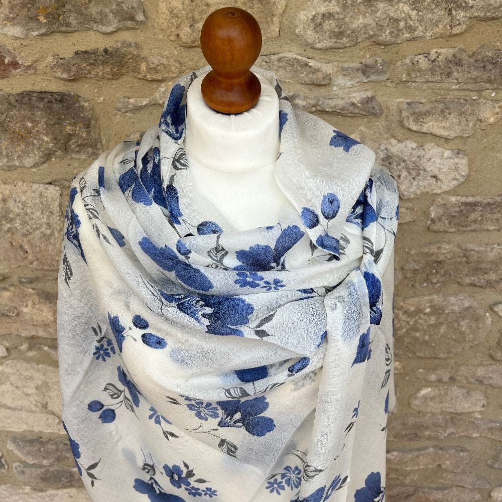 A gossamer cashmere scarf on a mannequin against a stone wall background. 
