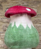Pure wool felted toadstool mushroom pet cave next to a stone wall. 