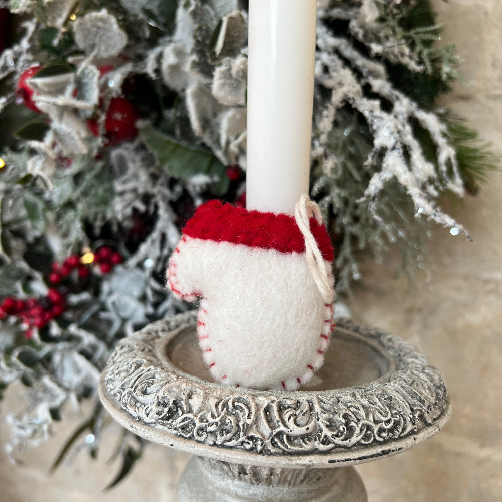 Reverse side of Handcrafted Christmas Glove (Mitten) with Embroidered Snowflake and Beaded Decoration against a stone wall backdrop and Seasonal Christmas Wreath