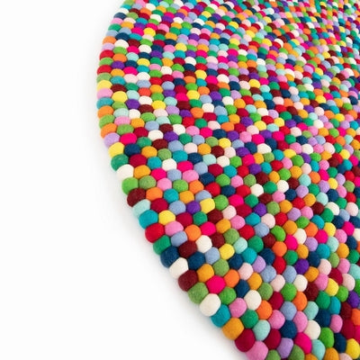 Rectangular Handcrafted Felted Wool Rugs - Multicolour available by Douée on a natural colour carpet in a room with tables and a natural colour sofa against a neutral wall with a green plant for decoration. 