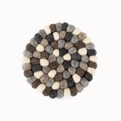 This handcrafted felted wool trivet combines a warm colour design with durable, sustainable materials. Shown on a white backdrop as a close up. 