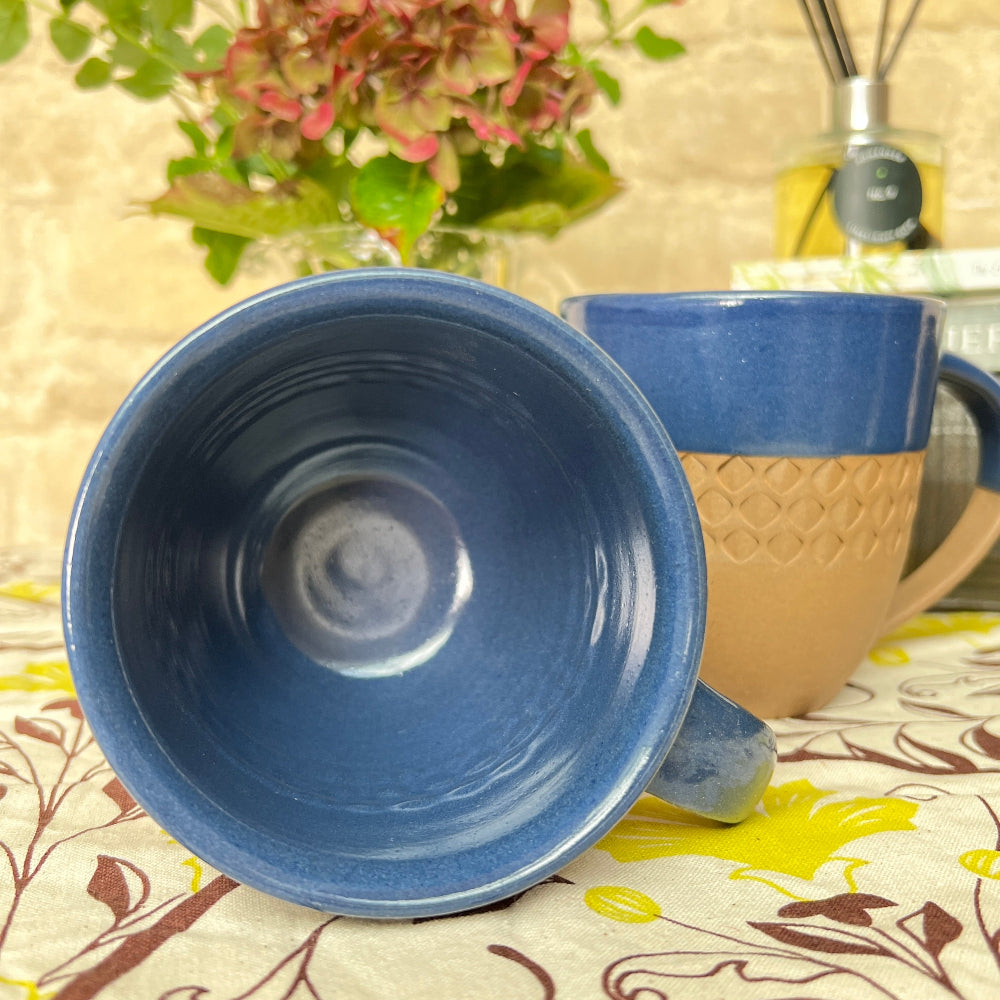 Hand Thrown and Decorated Mug - Bhaktapur Midnight Blue on a table with a Douée tablecloth, coffee, room diffusers and fresh flowers against a cotswold stone wall
