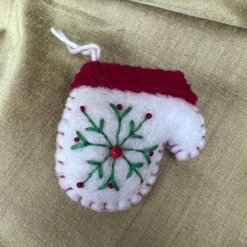 Handcrafted Christmas Glove (Mitten) with Embroidered Snowflake and Beaded Decoration against a stone wall backdrop and Seasonal Christmas Wreath