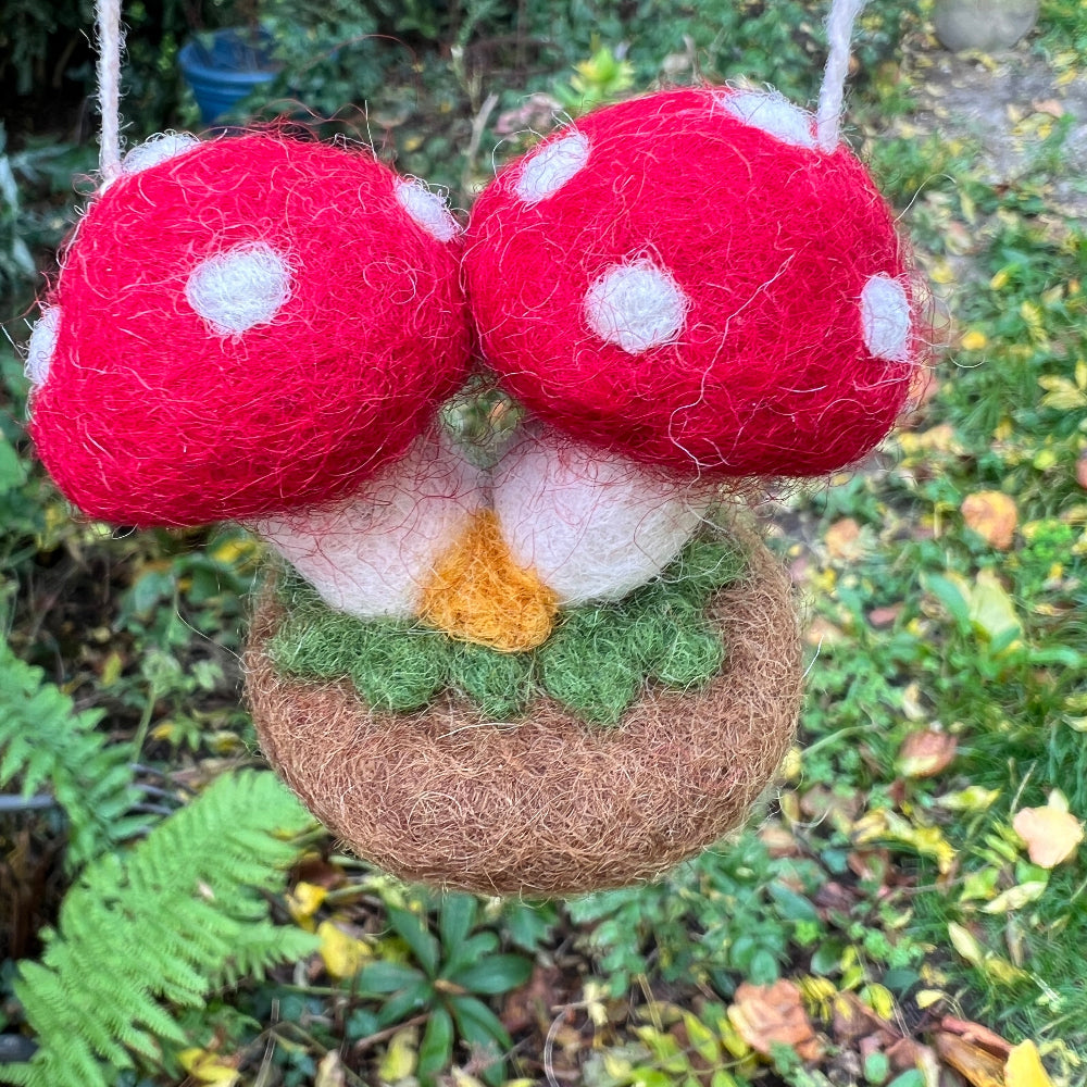 Handcrafted Felted Wool &#39;Woodland Toadstools&#39; hanging from a tree with red berries and green leaves.