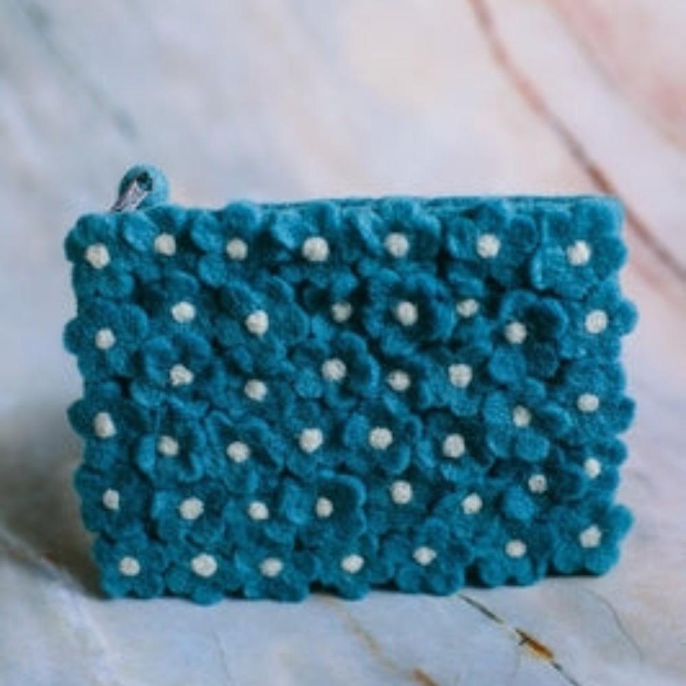 A turquoise pure wool clutch with a daisy pattern, featuring a zipper and a polka and dot and floral design.
