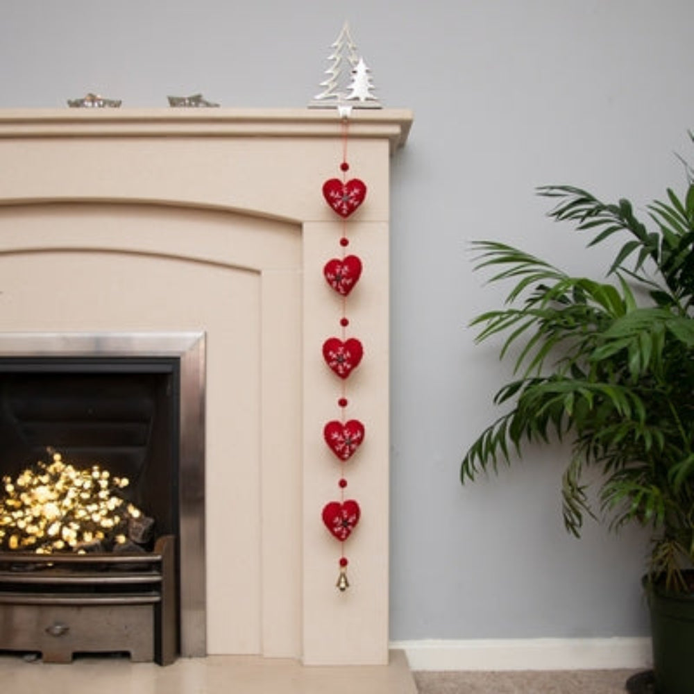 Hand-crafted from pure felted wool, this elegant Heart garland features individually embroidered details and decorative button centres.

The 81cm strand drapes beautifully across walls, doorways, or festive trees, with a charming brass bell that chimes softly as curtains move.

Each heart is meticulously cut and finished by hand, making it a timeless seasonal piece worthy of display year after year. A thoughtful gift for those who appreciate artisanal craftsmanship and refined holiday décor.