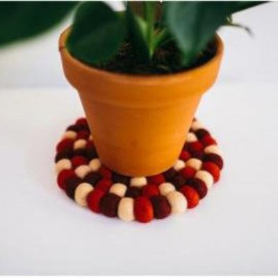 Handcrafted Felted Wool Mat / Trivet - Red & Cream on a wor surface.