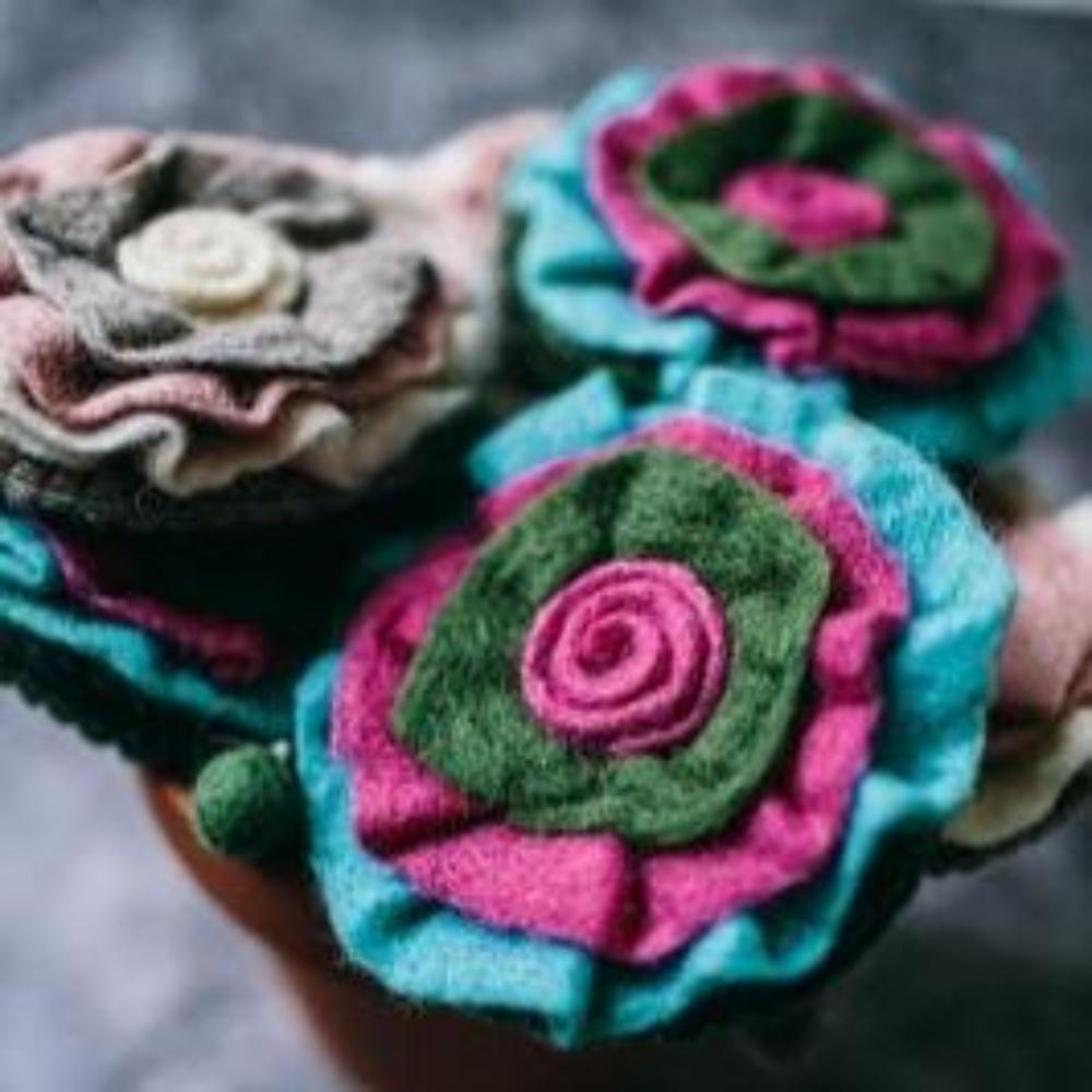 A childs handcrafted Felted Wool Purse - Rosette Style - Green & Cerise or Cream & Pink with zip fastening shown on a marble surface