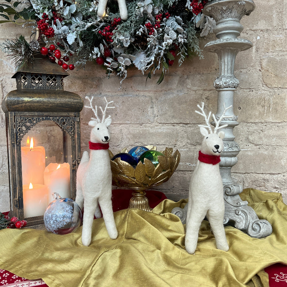 Handcrafted Felted Wool Winter Reindeer with Red Scarf against a stone wall with Candlestick and Christmas Decorations