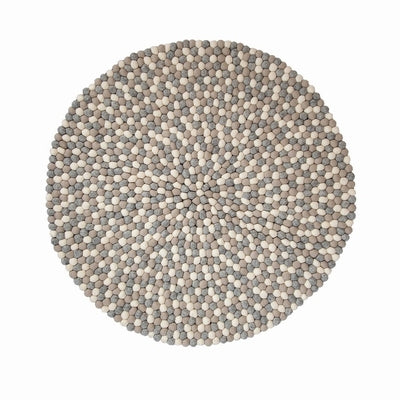 Handcrafted Felted Wool Rugs - Cream, Browns and Grey by Douée on a natural colour carpet in a room with tables and a natural colour sofa against a neutral wall with a green plant for decoration. 