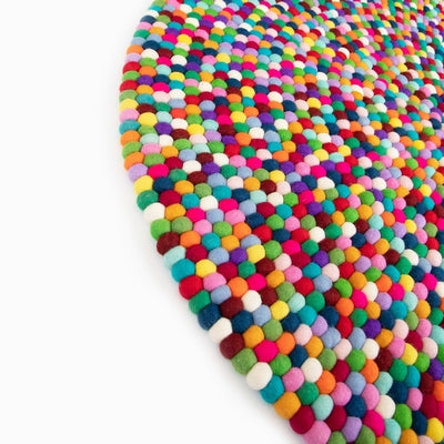 Handcrafted Felted Wool Rugs - Multicoloured on a natural colour carpet in a room with tables and a natural colour sofa. 