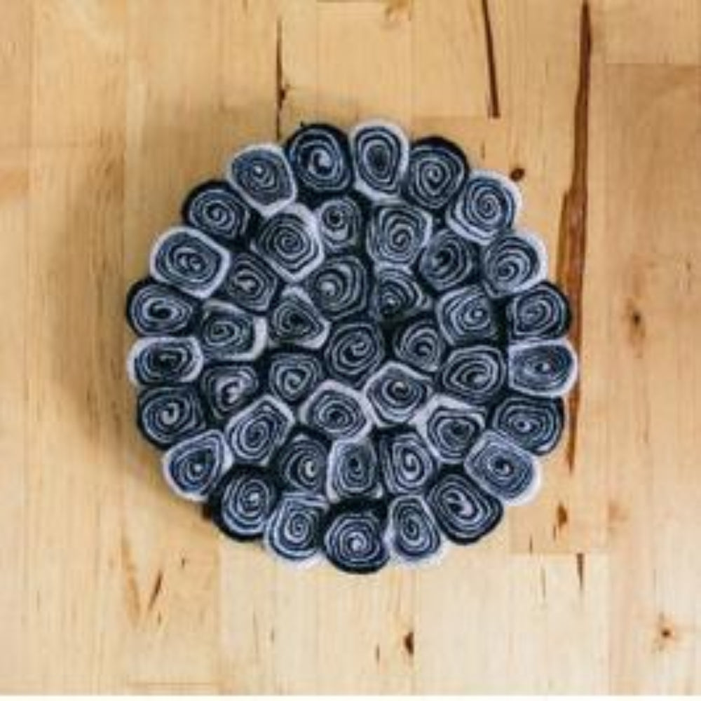 Handcrafted Felted Wool Trivet / Mat - Black & Grey Swirl on a wooden table.