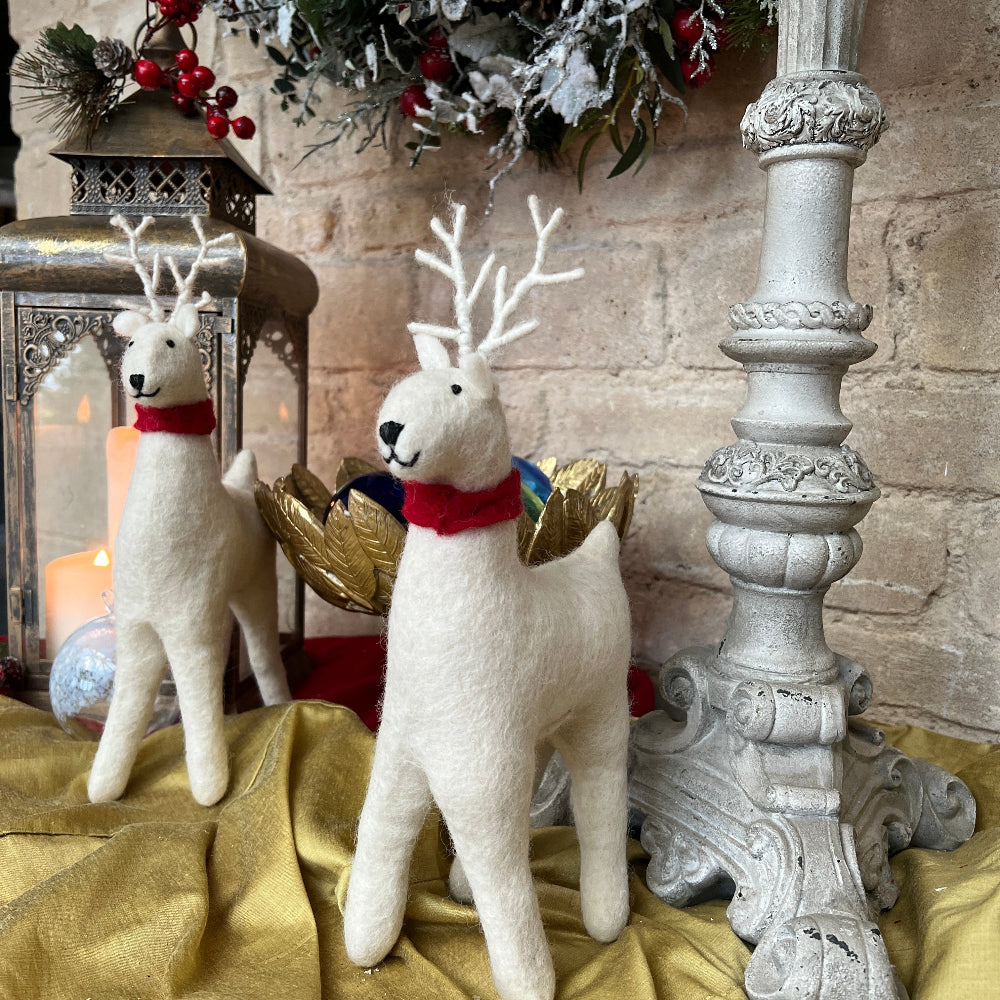 Handcrafted Felted Wool Winter Reindeer with Red Scarf against a stone wall with Candlestick and Christmas Decorations