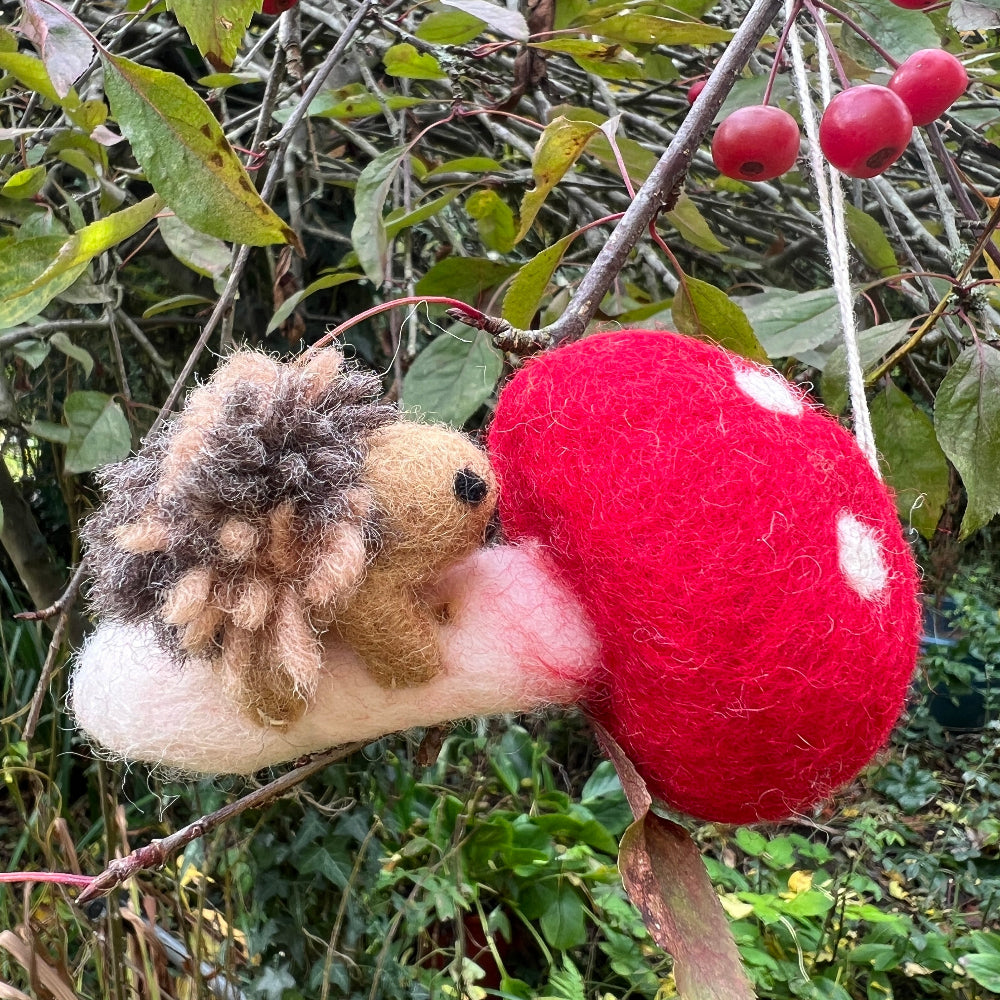 Handcrafted Felted Wool 'Woodland Toadstool' with Hedgehog hanging from a countryside tree with red berries