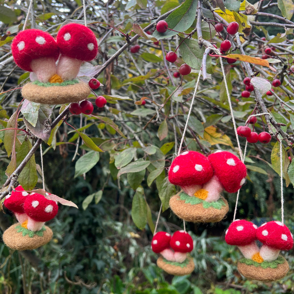Handcrafted Felted Wool &#39;Woodland Toadstools&#39; hanging from a tree with red berries and green leaves.