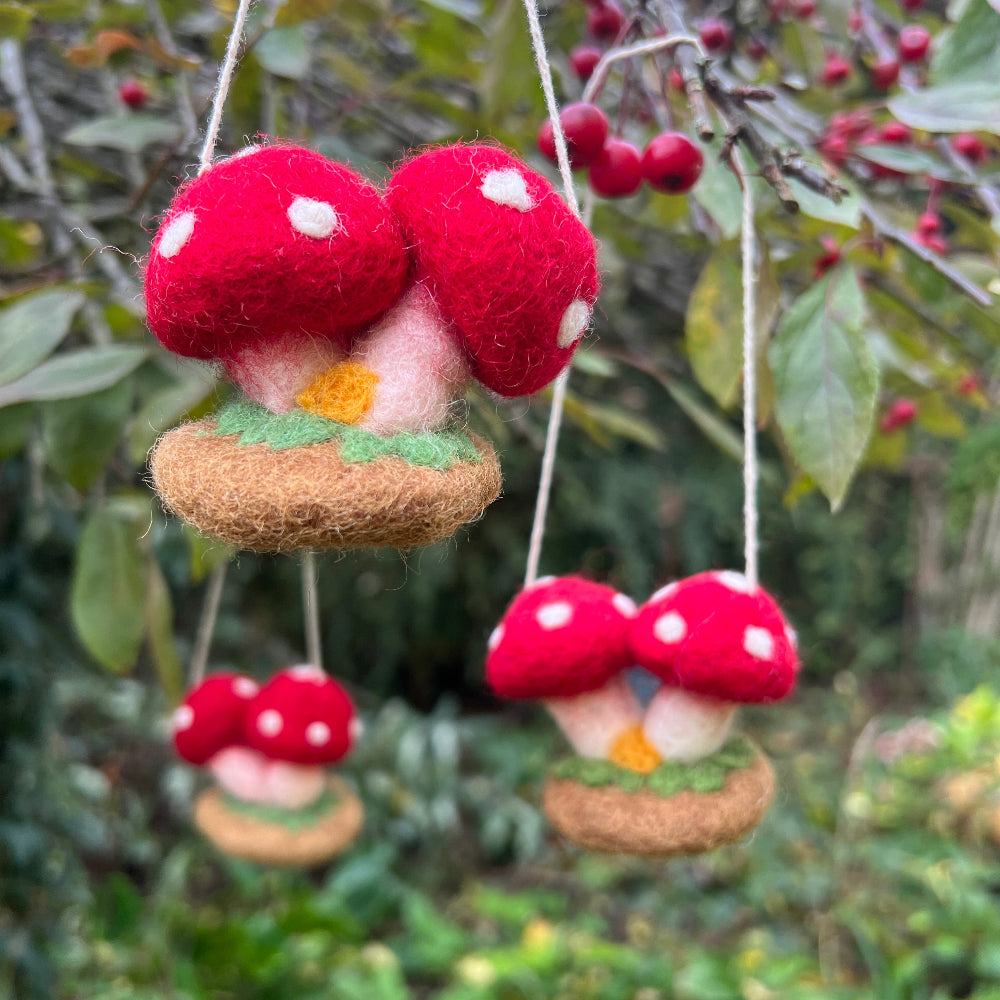 Handcrafted Felted Wool &#39;Woodland Toadstools&#39; hanging from a tree with red berries and green leaves.