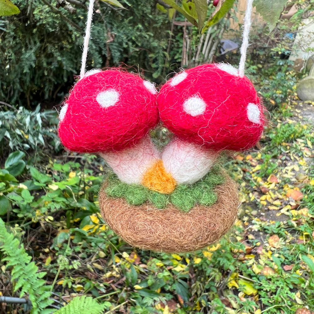 Handcrafted Felted Wool &#39;Woodland Toadstools&#39; hanging from a tree with red berries and green leaves.