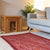 A rectangular, burgundy-colored felted wool rug with a floral pattern, placed on a gray sofa in a living room setting.