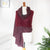 A Handwoven Cashmere Reversible Pashmina in Claret & Grey colours on a mannequin against a white background with a green plant decoration. 
