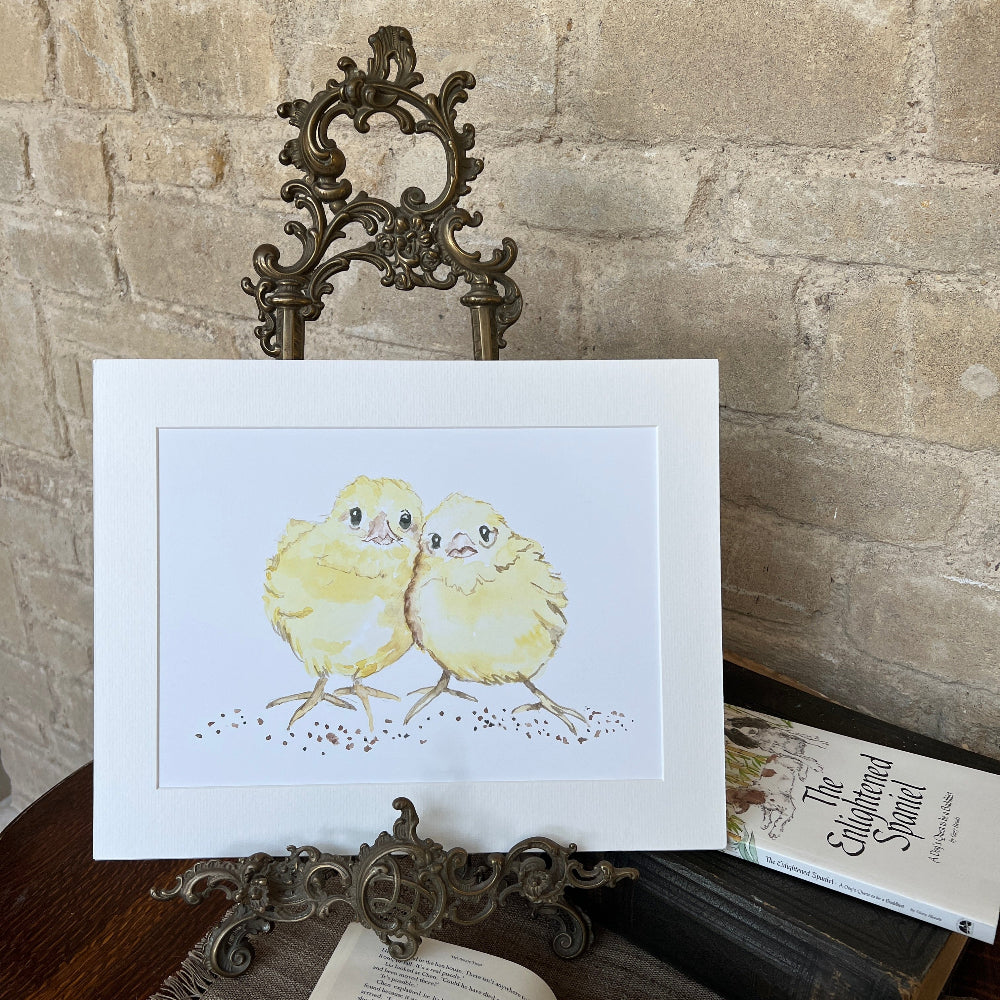 &#39;Cheek to Cheek&#39; is a charming limited edition watercolor print by artist Linda Beazley.

This mounted artwork brings a splash of elegance and fun to any room, making it a delightful gift or a joyful addition to your collection. Don&#39;t miss out on the chance to welcome this captivating piece into your space!  Shown on a brass stand, against a stone wall with books on a table. 