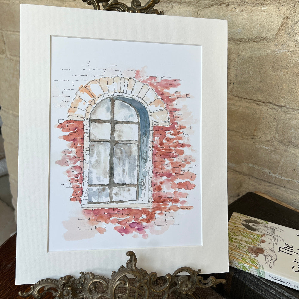 &quot;Through a Santa Fé Window&quot; is an exquisite limited edition watercolour print by artist Linda Beazley.

This elegantly mounted piece captures the serene beauty and subtle charm of Santa Fé, offering a refined aesthetic that enhances any interior.&amp;nbsp; The artwork presents a harmonious blend of light, shadow, and colour, inviting contemplation and admiration. Shown on a brass stand with books against a stone wall background. 