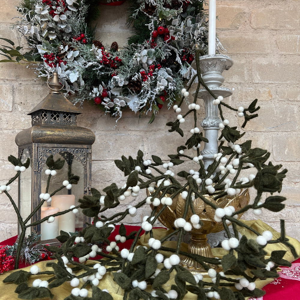 Our Mistletoe offers a refined touch to your holiday décor, perfect for creating memorable Christmas gatherings. Made from felted New Zealand wool, its pliable wired stems let you adjust the shape to suit your style.

This durable and eco-friendly ornament measures around 12&quot; (30.48 cm) long, designed for enduring festive charm year after year. Shown in a gold decorative bowl, with candles and festive decoration against a cotswold stone wall. 