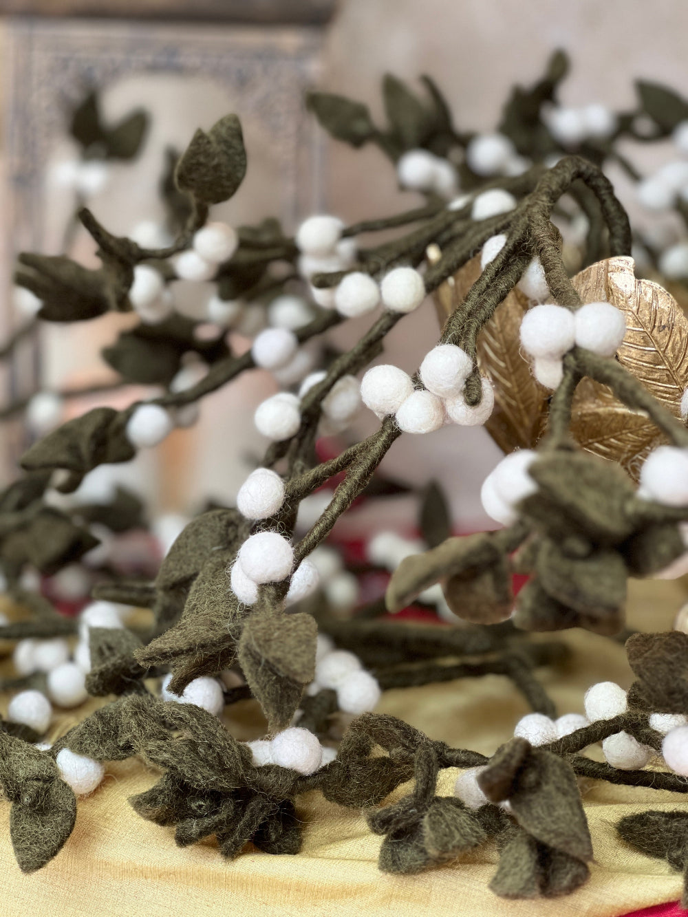 Our Mistletoe offers a refined touch to your holiday décor, perfect for creating memorable Christmas gatherings. Made from felted New Zealand wool, its pliable wired stems let you adjust the shape to suit your style.

This durable and eco-friendly ornament measures around 12&quot; (30.48 cm) long, designed for enduring festive charm year after year. Shown in a gold decorative bowl, with candles and festive decoration against a cotswold stone wall. 