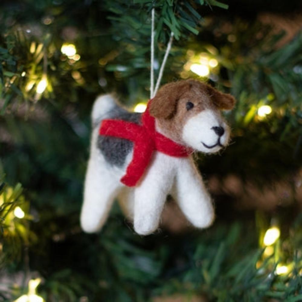 Meet &#39;Patch&#39;, a charming felted wool dog that brings artisanal character to any space.

This companion features a distinctive patchwork design with rich brown tones, complemented by a striking crimson scarf. Meticulously hand-stitched from premium wool, each piece showcases the craftsmanship of its maker.

Shown on gold silk fabric with candles, festive holly, decorative accents against a cotswold stone wall. 