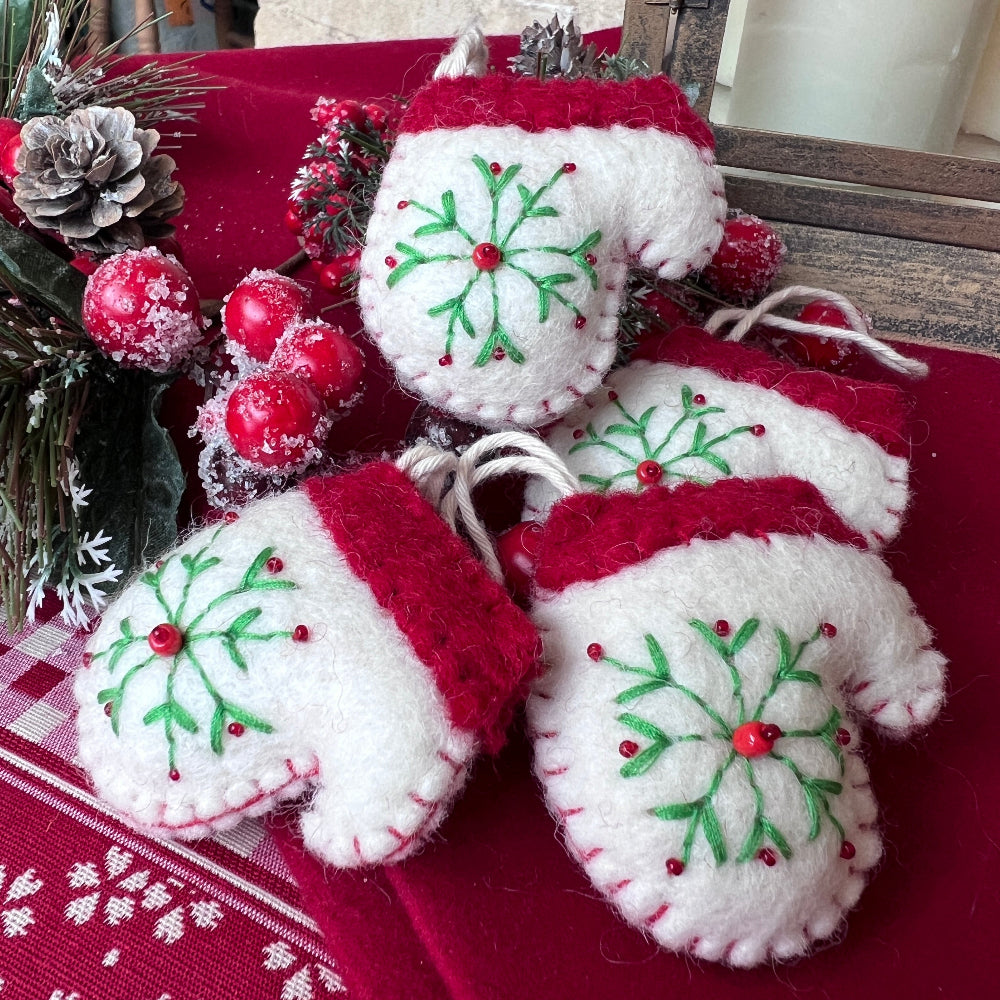 Handcrafted Christmas Glove (Mitten) with Embroidered Snowflake and Beaded Decoration against a stone wall backdrop and Seasonal Christmas Wreath